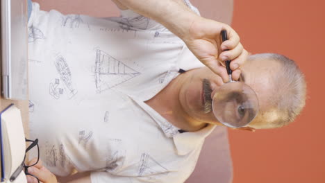 Vertical-video-of-Old-man-looking-at-camera-with-magnifying-glass.